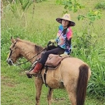 Person in a hat on a horse in a grassy field.